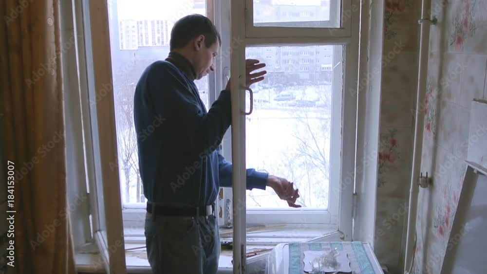 Man repairs wood window. Replace broken glass on window Man repairs wood window. Replace broken glass on window