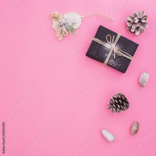 Christmas composition of black gift box, decoration and pine cones on pink background. New year concept. Flat lay. Top view