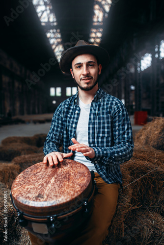 Photography Young male drummer against african wooden drum