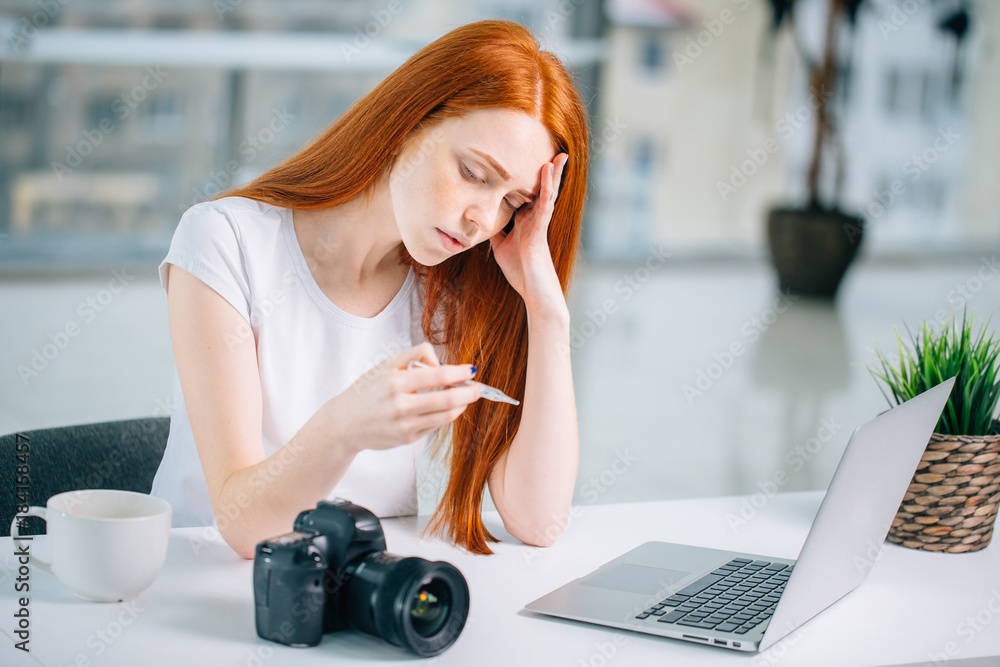 Φωτογραφία redhead girl with thermometer sitting on laptop and looking at network what to d