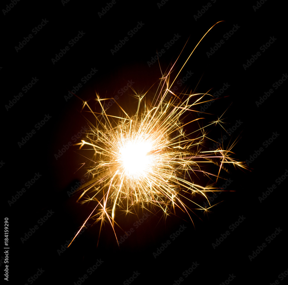 Bright sparks on deep black background closeup. Party holiday sparkler isolated on black