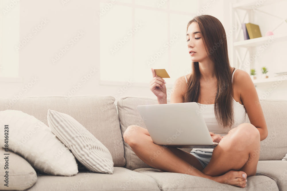 Serious young girl shopping online sitting on the sofa Serious young girl shopping online sitting on the sofa