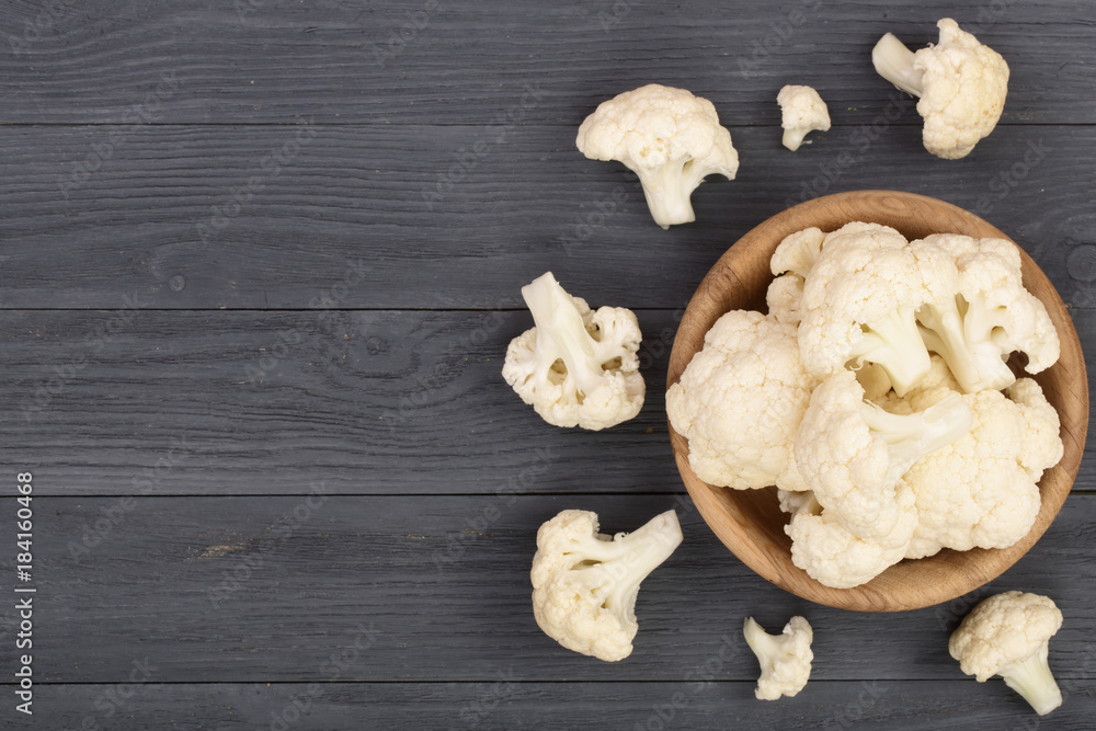 Fresh cauliflower cut into small pieces on black wooden background with copy space for your text. Top view. Flat lay Fresh cauliflower cut into small pieces on black wooden background with copy space for your text. Top view. Flat lay
