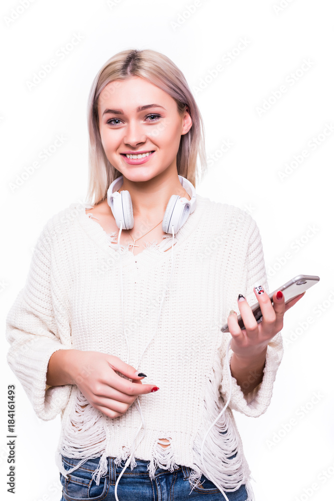 Portrait of a joyful casual woman with long blonde hair listening music with earphones and holding mobile phone isolated over white Portrait of a joyful casual woman with long blonde hair listening music with earphones and holding mobile phone isolated over white