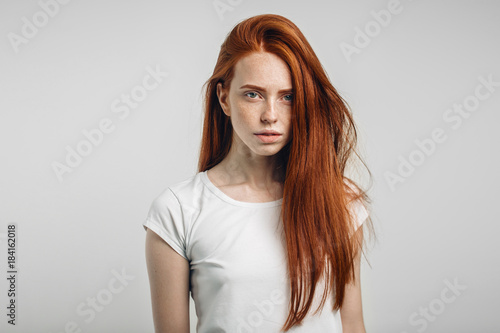 redhead teenage girl with healthy freckled skin looking at camera with serious emotion photo