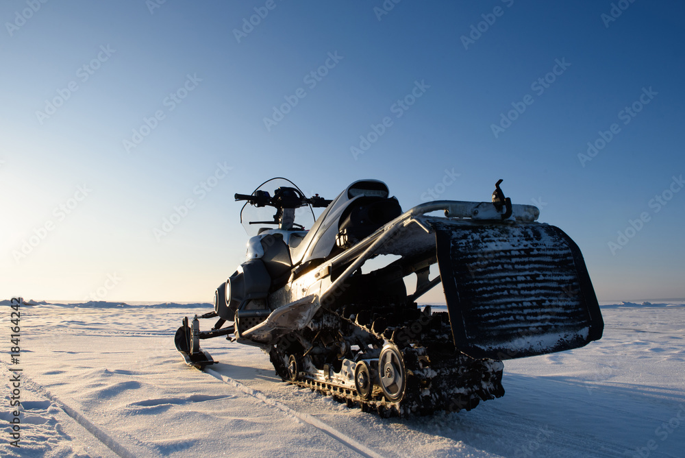 The snowmobile stands on the ice of the lake in clear weather
The snowmobile stands on the ice of the lake in clear weather