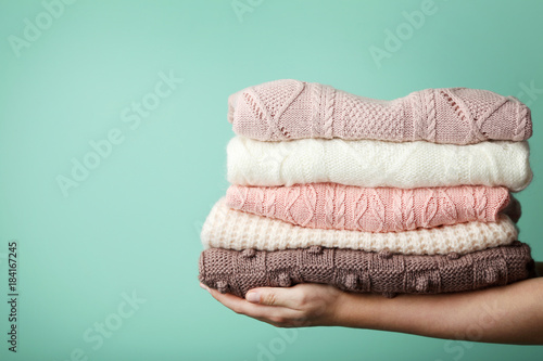 Female hands holding stack of knitted sweaters