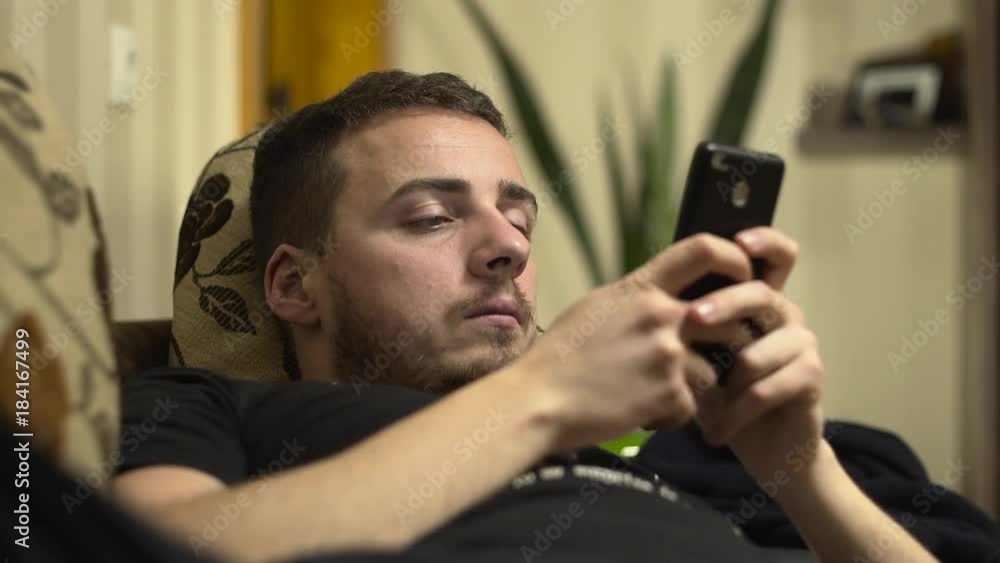 Medium shot of man write sms on cellphone on bed Medium shot of man write sms on cellphone on bed