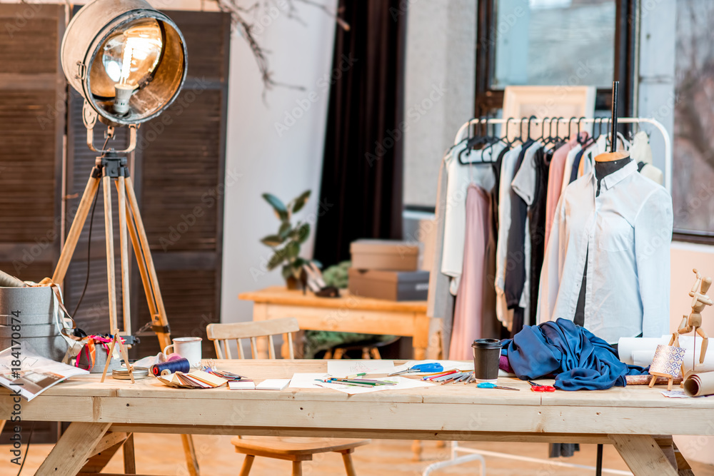 Working place of fashion designer with tailoring tools and drawings on the  table with clothes on the background Stock Photo | Adobe Stock