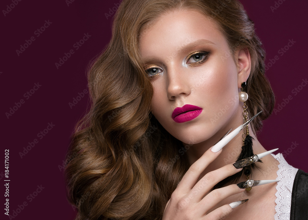 Beautiful redhair model: curls, bright gold makeup, long nails and red lips. The beauty face. Portrait shot in the studio on a brown background.
