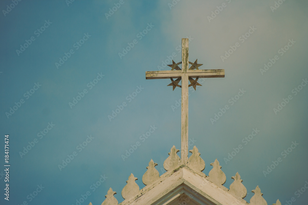 Metal holy cross or crucifix on the top of white church with blue sky in the background in vintage style. Metal holy cross or crucifix on the top of white church with blue sky in the background in vintage style.