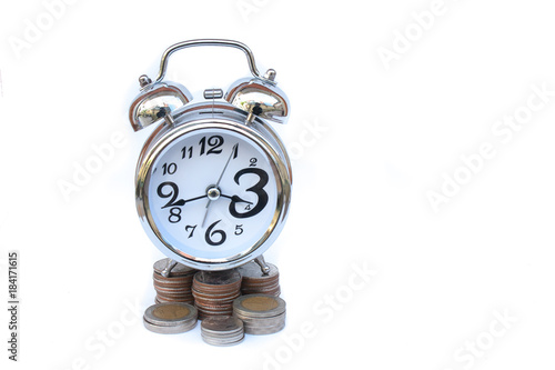 Time is Money Concept : Alarm clock put on stack of silver money coins (Baht) isolated on white background. (Selective focus) photo