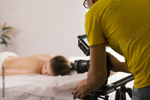 Behind the scenes of medicine video film shooting - nude young woman lying on massage table photo