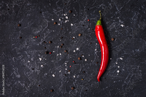 Red hot chili pepeprs and peppercorns on black stone background, top view