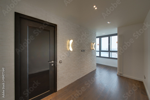 The room with a white brick wall  lamps and a dark wooden door