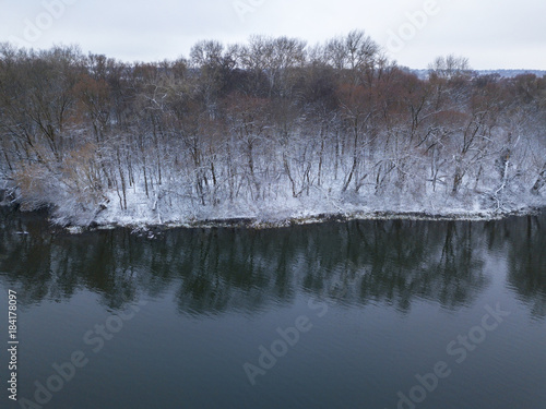 View from height to the winter forest covered with snow and standing on the river bank