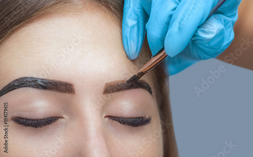 Obraz na płótnie makeup artist applies paint henna on previously plucked, design, trimmed eyebrows in a beauty salon in the session correction