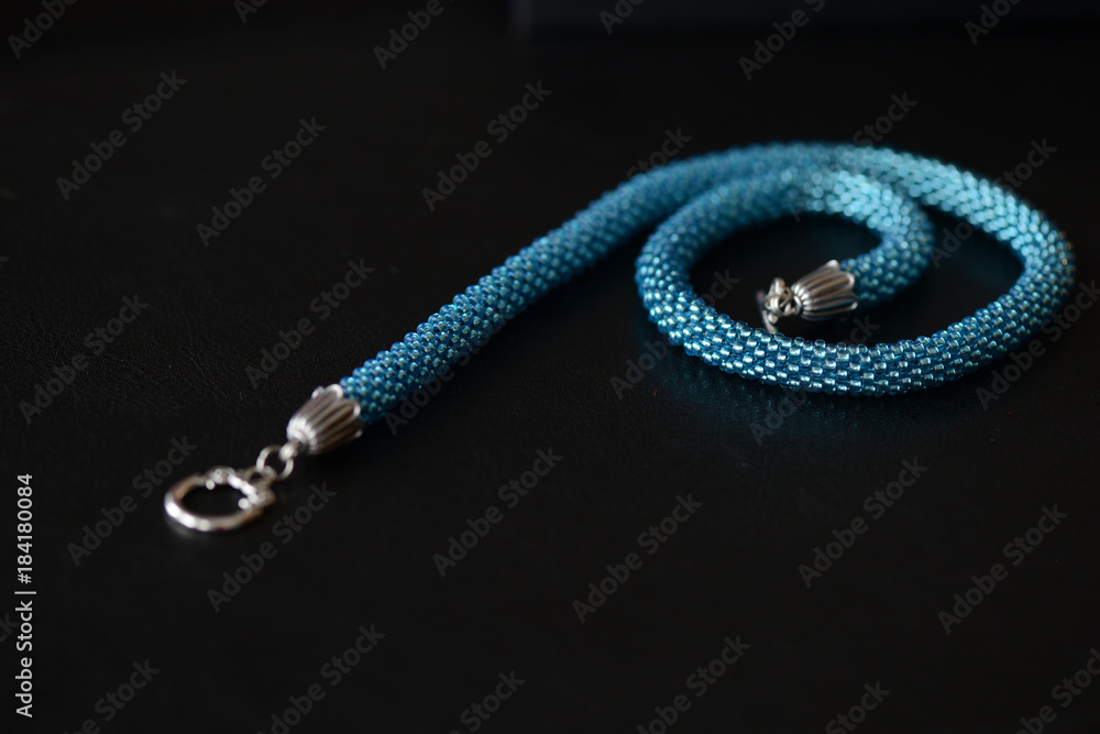 Fototapeta premium Beaded necklace of turquoise color on a dark background close up