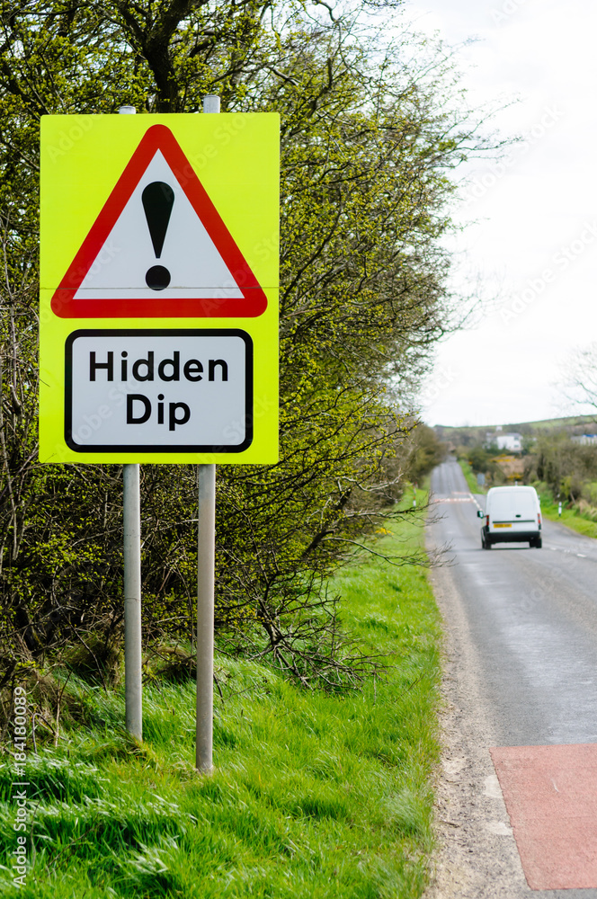 Roadsign on a rural road warning of a hidden dip in the road