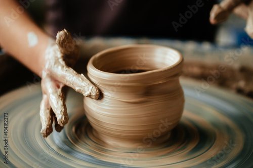 Valokuvatapetti Hands of young potter, close up hands made cup on pottery wheel