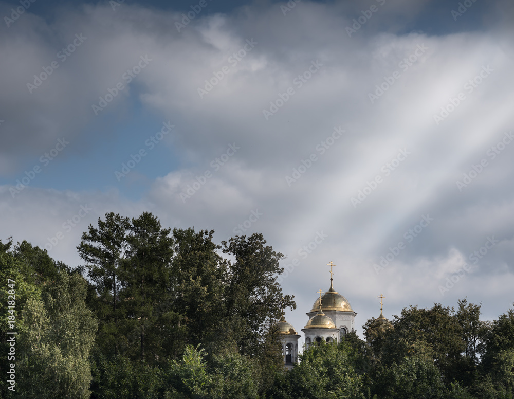 Beautiful church domes surrounded by trees under a blue sky with some clouds
