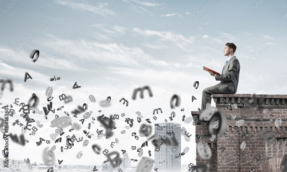 Man on roof edge reading book and symbols flying around Man on roof edge reading book and symbols flying around