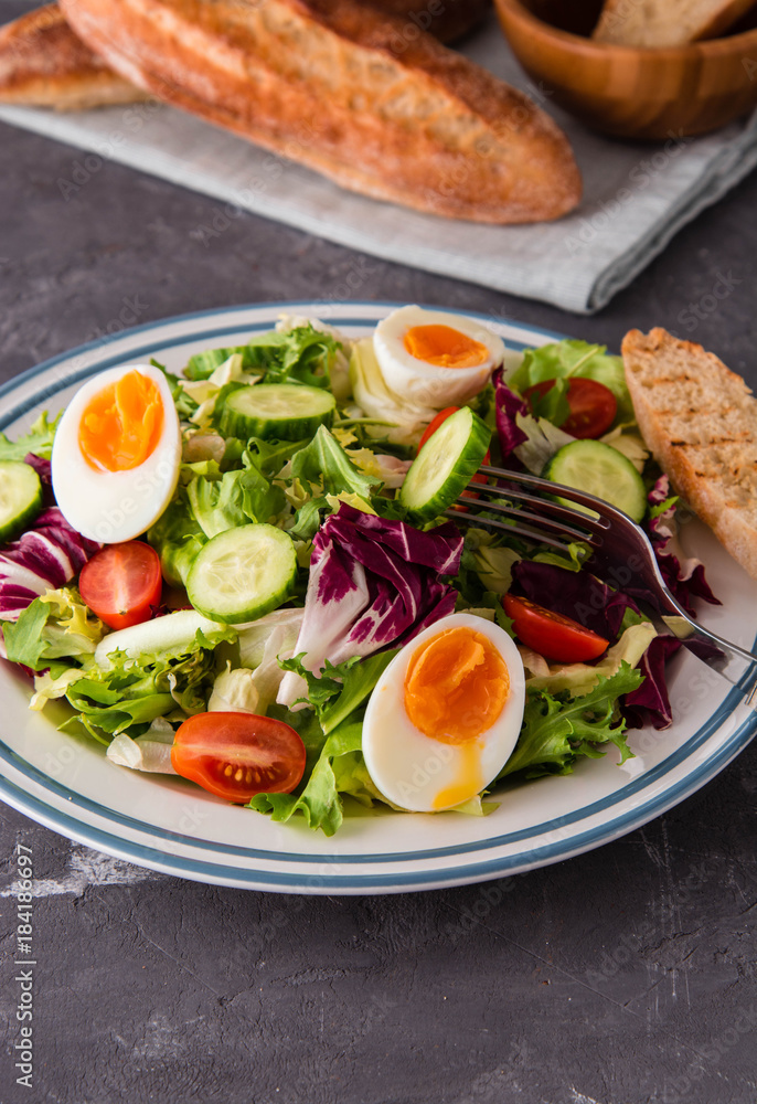 Fresh salad with egg, tomato, cucumber and toasted baguette.