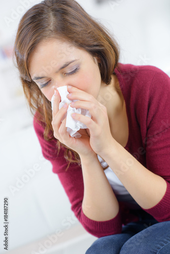 unhappy woman with paper napkin blowing nose