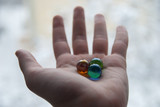 Marble. Red, green and blue glass small balls in a men hand