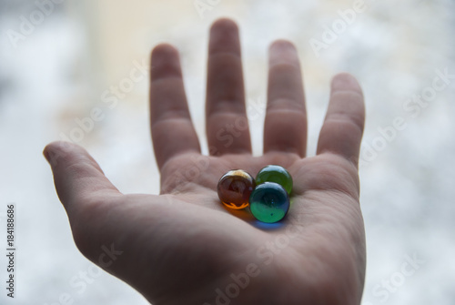 Marble. Red, green and blue glass small balls in a men hand