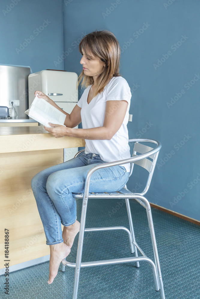 Portrait of smiling young woman reading book in kitchen at home Portrait of smiling young woman reading book in kitchen at home