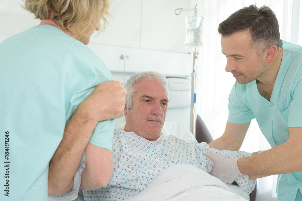 Fototapeta premium Medical workers helping patient rise from bed