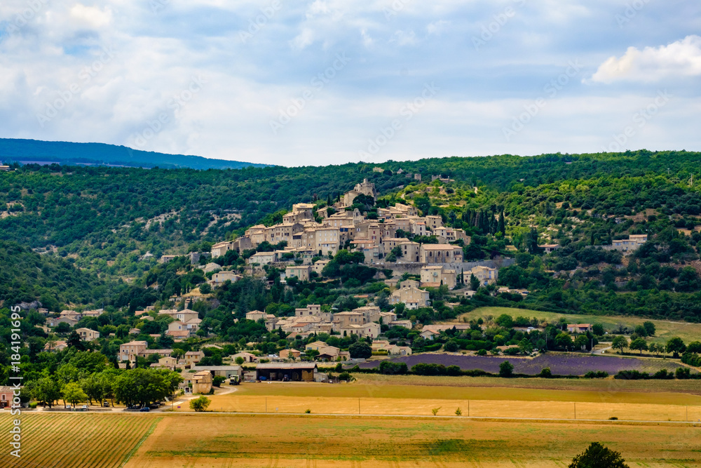 Vue sur le village de Simiane-la-Rotonde. Champ de lavande en fleurs au piet du village.