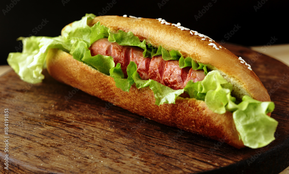 delicious homemade Hot dog with salad and sesame seeds closeup on wooden Board,black background delicious homemade Hot dog with salad and sesame seeds closeup on wooden Board,black background