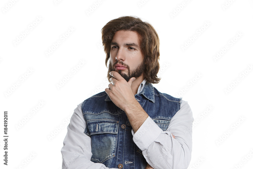 Portrait of pensive thoughtful young ushaven man pondering and touching his beard while thinking over prospective job offer, feeling hesitant to accept it. Doubt, hesitation and uncertainty concept Portrait of pensive thoughtful young ushaven man pondering and touching his beard while thinking over prospective job offer, feeling hesitant to accept it. Doubt, hesitation and uncertainty concept