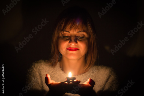 Girl holds a candle in her arms in the dark