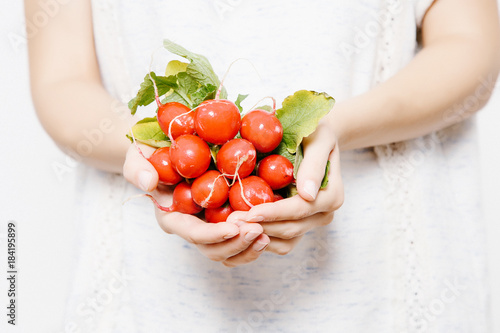 The girl holds a radish in her hands. A young woman with a radish.