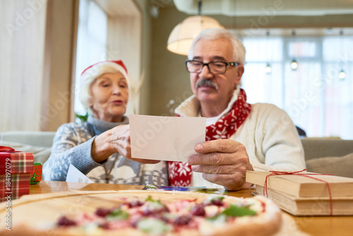Portrait of loving senior couple looking at family photographs during Christmas dinner in cafe