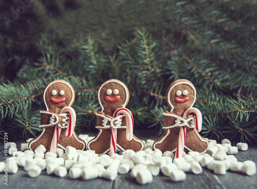 Gingerbread men with candy cane snowflakes laying on grey wood background. Christmas or New Year composition. Christmas card.