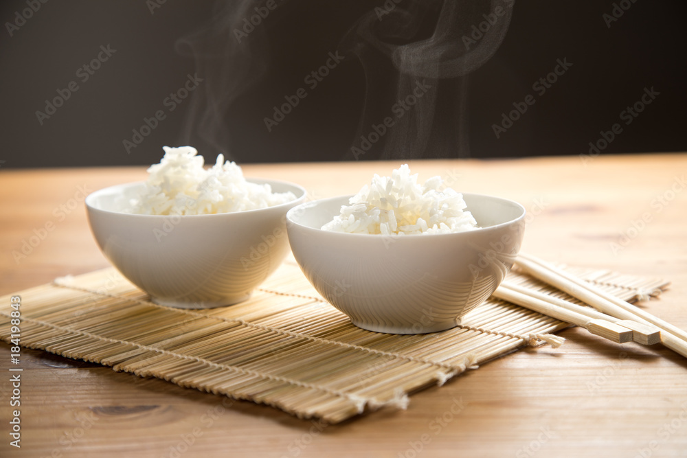 Zwei Schalen Basmati Reis mit Stäbchen auf Matte Zwei Schalen Basmati Reis mit Stäbchen auf Matte
