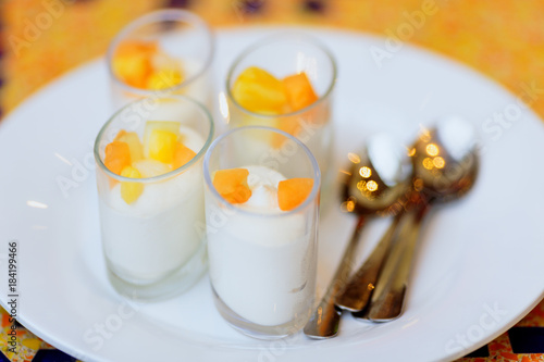 four delicious white dessert souffle with orange fruits on white plate with tea spoons
