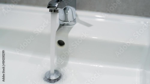 Home water faucet closeup, flow open spilling water into the drain