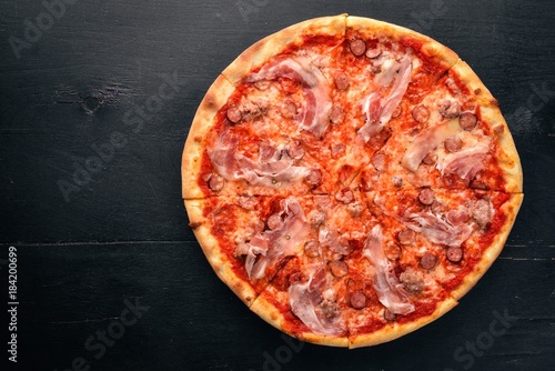 Pizza Lardon. Bacon, cherry tomatoes, sausage salami. On a wooden background. Top view.