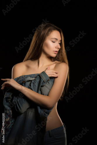 Lovely young woman covering her body with a jeans jacket in the dark