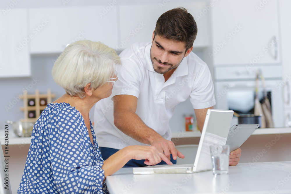 Obraz premium adult grandson teaching his grandma using a computer
