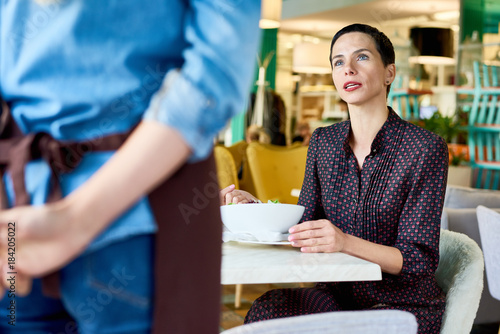 Portrait of elegant adult woman complaining about food quality and taste to young waitress in cafe, copy space