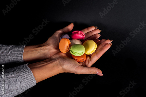 colored macaroons in palms on a black background.