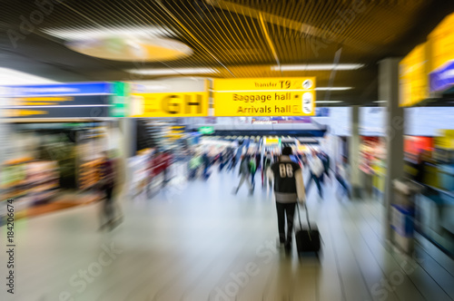 People walking towards the departure gates at an airport, blurred to show movement and speed.