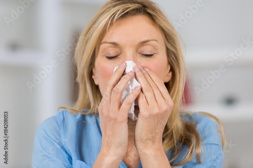 woman with cold blowing her nose