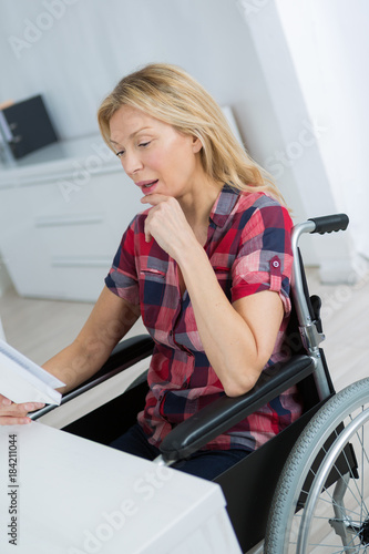 pleasant disabled woman sittign in the wheelchair at home photo